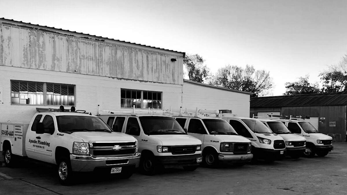 Apache Plumbing's fleet of six lettered trucks and vans outside the shop
